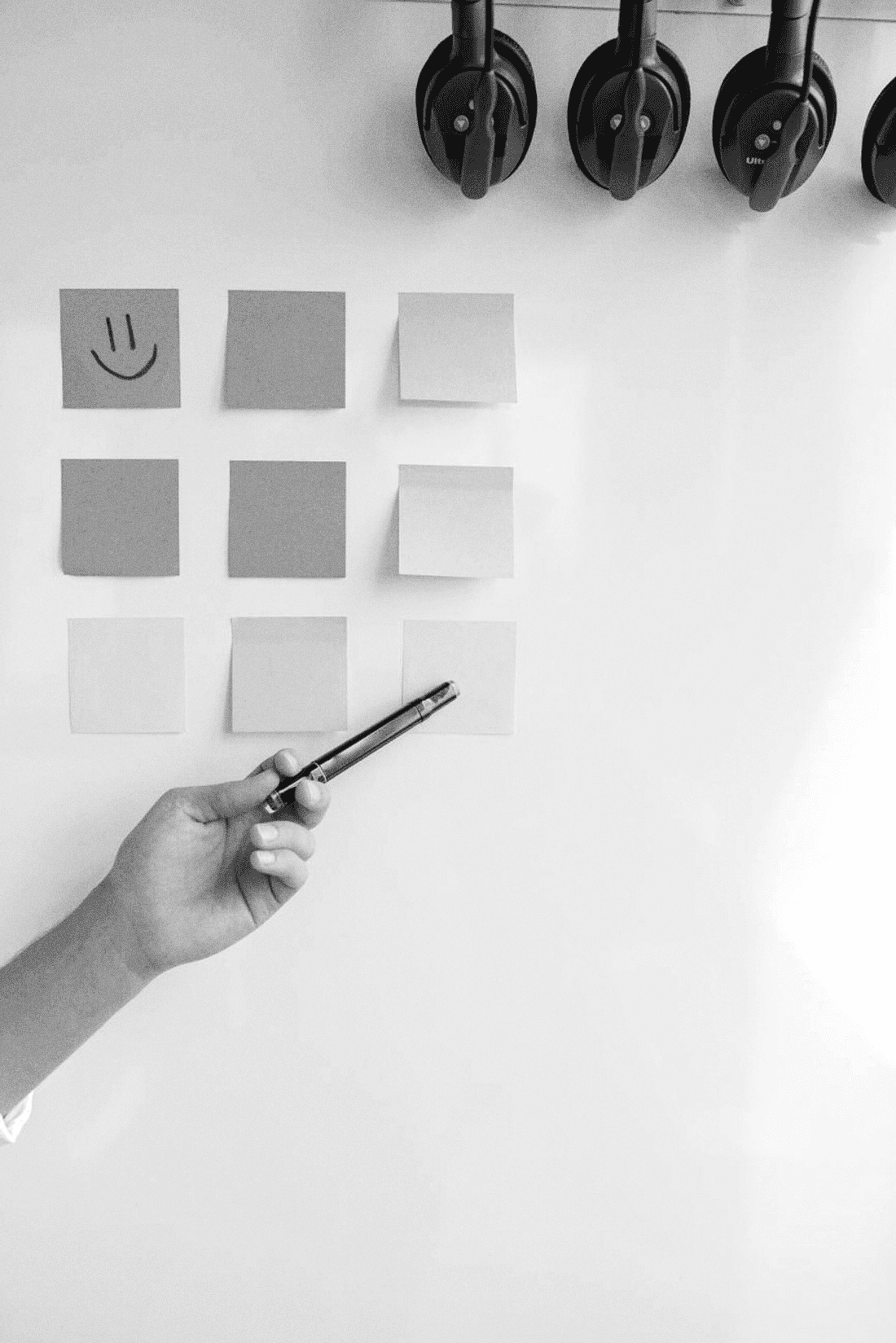 Main désignant des notes sur un tableau, séance de priorisation.