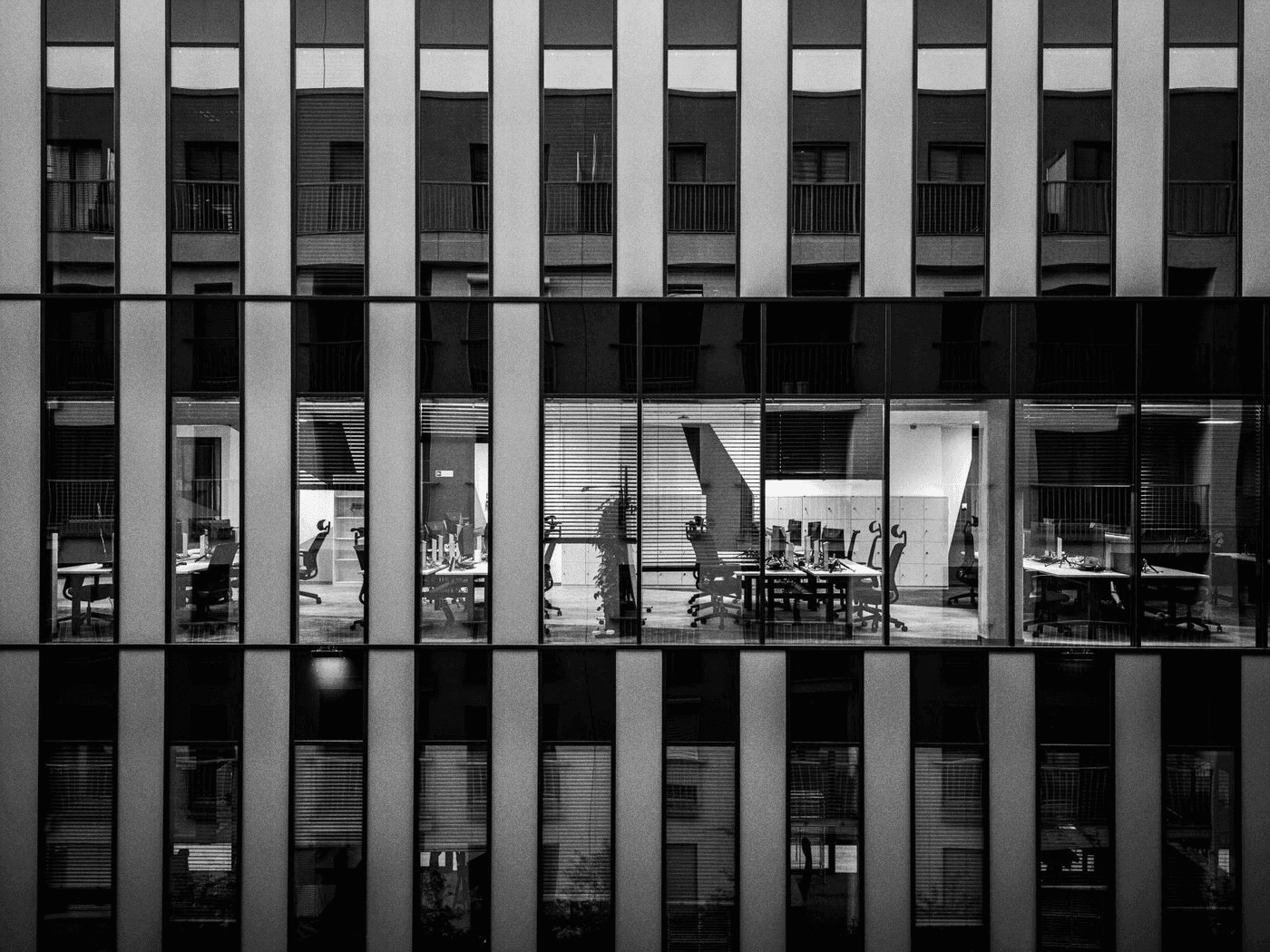 Bureaux éclairés dans un immeuble de verre contemporain.